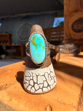 Load image into Gallery viewer, Turquoise ring on a decorative stand with a rustic background
